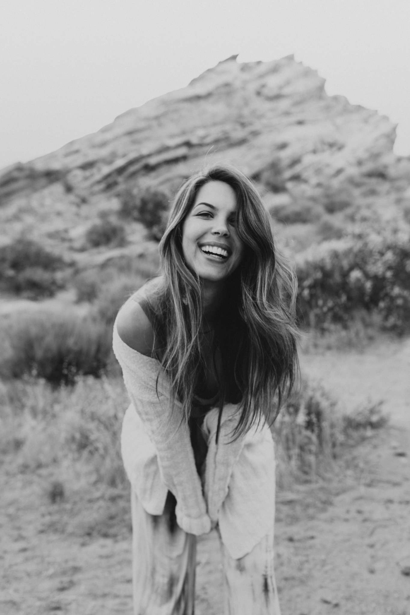 Sarah laughing outdoors beside a rocky hillside