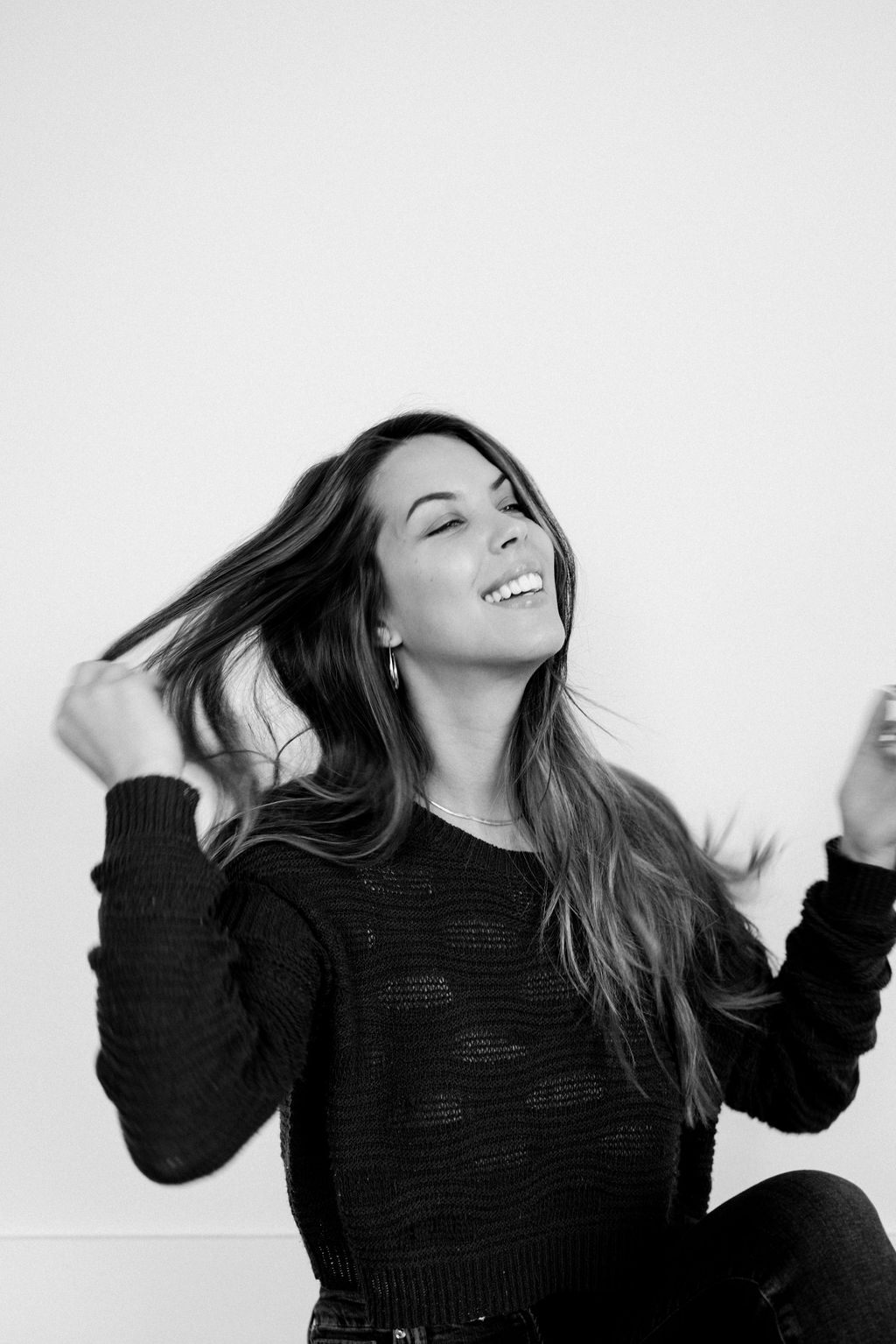 Sarah smiling in a black sweater in a light-filled studio
