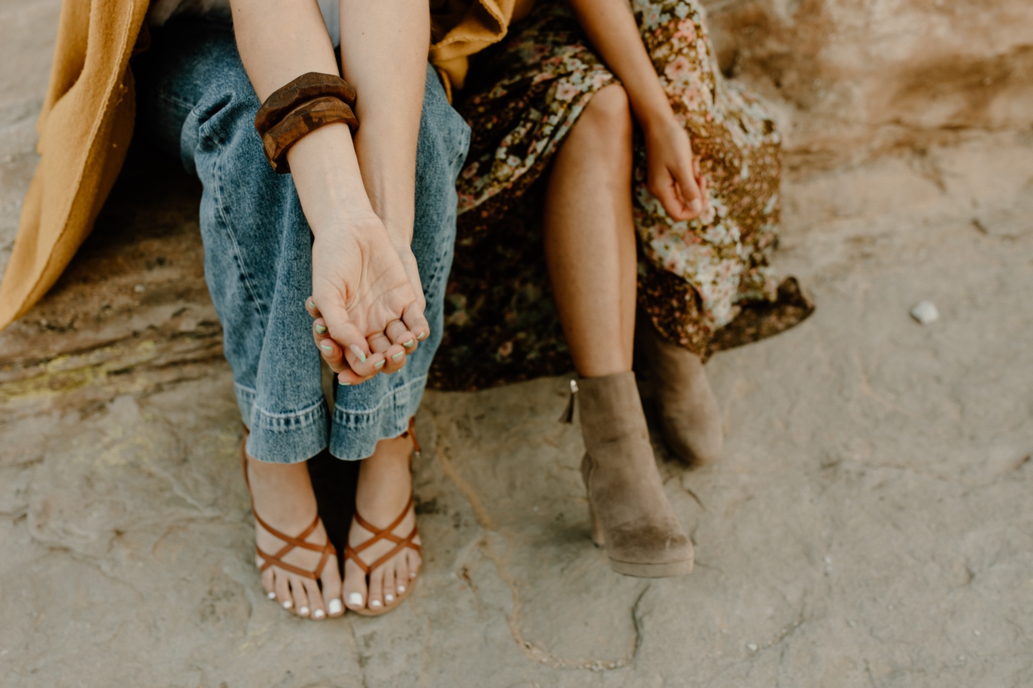 Two women sitting together on a rock, their hands resting on their knees